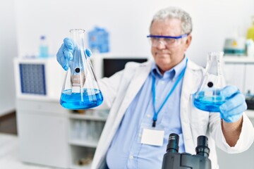 Fototapeta premium Middle age grey-haired man wearing scientist uniform holding test tube at laboratory