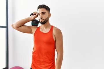 Young arab man training with kettlebell at sport center