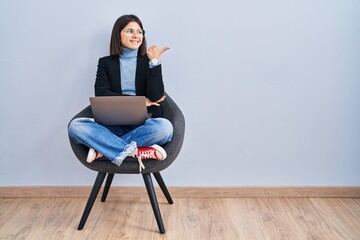 Young hispanic woman sitting on chair using computer laptop smiling with happy face looking and...