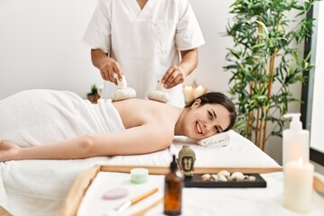 Fototapeta na wymiar Young woman reciving herbal pouches thai massage at beauty center.