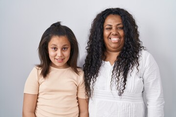 Mother and young daughter standing over white background winking looking at the camera with sexy expression, cheerful and happy face.