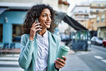 Young hispanic business woman wearing professional look smiling confident at the city speaking on...