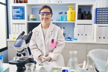 Hispanic girl with down syndrome working at scientist laboratory with a happy and cool smile on face. lucky person.