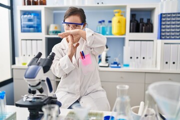 Fototapeta premium Hispanic girl with down syndrome working at scientist laboratory doing time out gesture with hands, frustrated and serious face