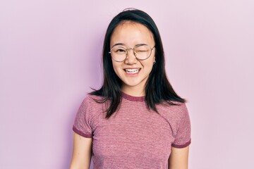 Fototapeta premium Young chinese girl wearing casual clothes and glasses winking looking at the camera with sexy expression, cheerful and happy face.
