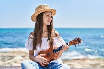 Adorable girl tourist smiling confident playing ukulele at seaside - obrazy, fototapety, plakaty