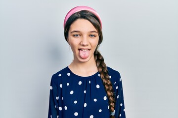 Young brunette girl wearing elegant look sticking tongue out happy with funny expression. emotion...