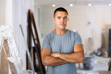 Portrait of a concentrated young man standing on a construction site indoors