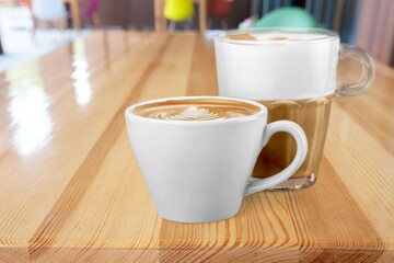 Ceramic cups of aromatic coffee with foam on the table in cafe