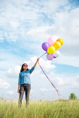 Woman holding balloons running on green meadow white cloud and blue sky with happiness Cheerful and relax. Hands holding vibrant air balloons play on birthday party happy times summer sunlight outdoor