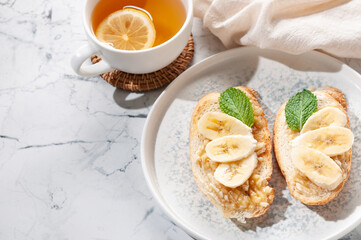 Snack sandwich with banana and mint greens. Tea with lemon.