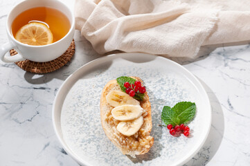 Appetizer sandwich with banana, red currant and mint greens. Tea with lemon.