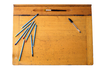 A photo of a vintage wooden school desk, featuring a hinged lid and penpencil groove, and with some coloured pencils, paint bush and a pen.
