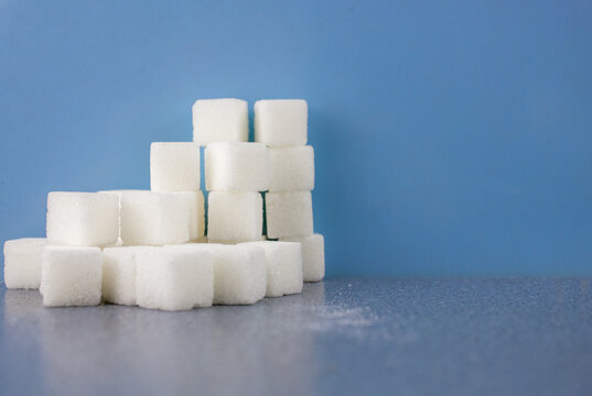 Cubes Of Sugar On A Blue Background With Place For Text..The Concept Of Sugar Product In The Kitchen. Natural White Lump Sugar.