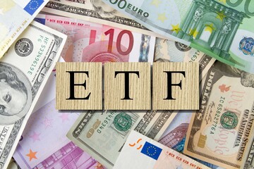 exchange-traded fund (ETF) is a type of pooled investment security. The word is written on money and gold background