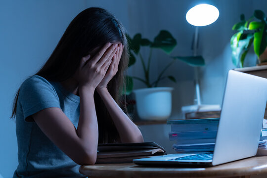 Tired, asian young student woman hand in covering face, study online sitting on desk at home, doing homework connecting to internet on laptop computer, studying late at night, learning and education.