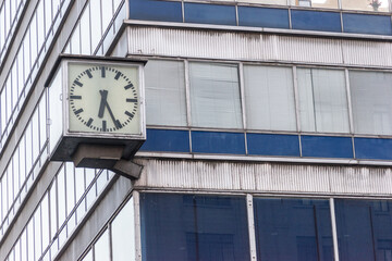 Clock on blue building with big windows. - Powered by Adobe
