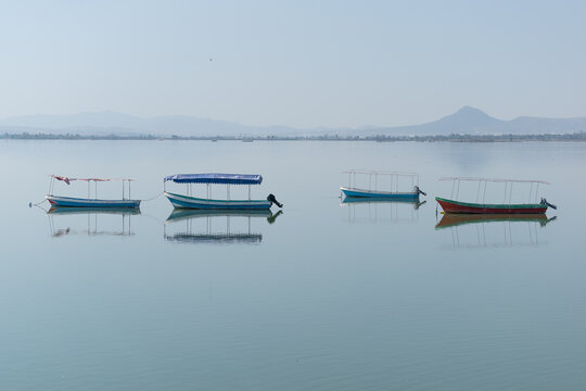Four boats floating in a lagoon of calm waters.
