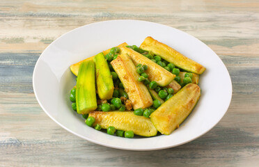 Vegetable dish of zucchini squash and green peas in white bowl
