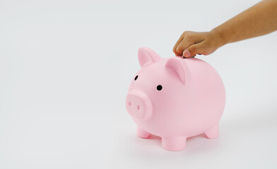 Hand little girl putting coin to piggy bank isolated on white background.