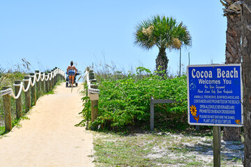 Sandy path over dunes with Cocoa Beach Welcomes You sign in Cocoa Beach, Florida. 