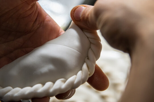 cook's hands making empanada repulgue