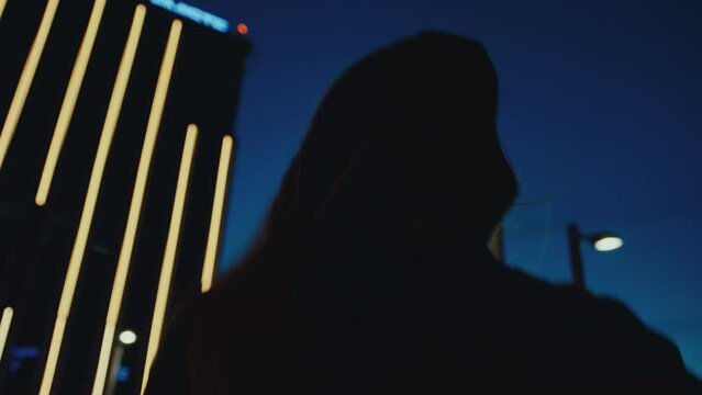 Hooded woman runs on rooftop and looks over edge, slow motion