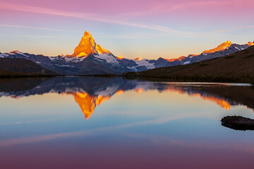 Beautiful sunset colors and cloudscape in the Swiss Alps in summer, with Matterhorn reflection in a...