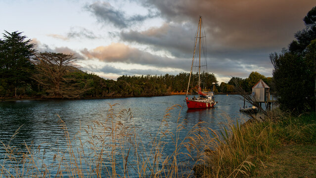 Yacht moored on the Catlins river at sunset, Owaka, southland, south island, Aotearoa / New Zealand.