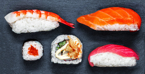 Sushi set on a black slate  background. Japan restaurant menu. Sushi with salmon, tuna and avocado. Top view.