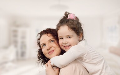 Mother and her little child happily smile and hug in apartment. Happy family.