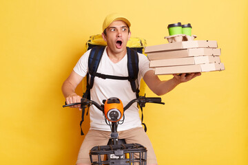 Shocked courier man holding pizza boxes and takeaway coffee cups, delivering order on bike with big...