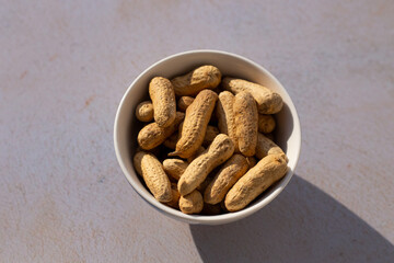 Maní tostado en un bol sobre un fondo de madera abstracto. Concepto de alimentos.