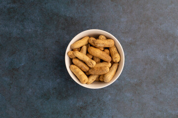 Maní tostado en un bol sobre un fondo azul abstracto. Concepto de alimentos.