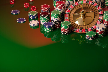 Casino. Gambling games theme.  Roulette wheel, dice and poker chips on the casino felt green table.