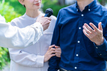 笑顔でマイクインタビューを受ける日本人男女