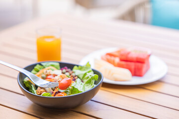 Breakfast. Vegetable salad, fruits such as watermelon, papaya, melon, passion fruit, orange juice and coffee. placed on a gray placemat