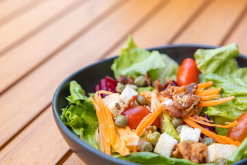 Breakfast salad with sauteed vegetables and with a fork placed on a wooden table