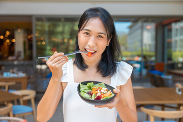 Woman eating Breakfast and play smart phone. Fruits such as watermelon, papaya, melon, passion fruit, orange juice and coffee. placed on a gray placemat