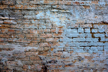An old exterior brick wall with lovely textured paint that is cracked and peeling.