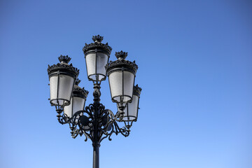 Fototapeta na wymiar Black vintage street lamp on the blue sky background