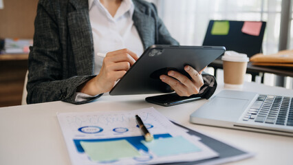 business documents on office desk with laptop and smart phone and graph business diagram and woman working