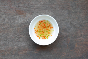 Pickled chilli in white ceramic cup on wooden table. Thai food.