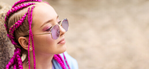 Portrait of a caucasian teenage girl with pink braids on a street background.Summer...