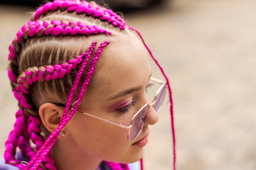 Portrait of a caucasian teenage girl with pink braids on a street background.Summer...