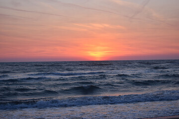 Obraz premium A beautiful sunset on the beach in the turbulent ocean