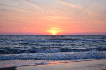 Fototapeta premium A beautiful sunset on the beach in the turbulent ocean
