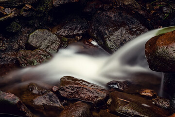 Water running through brown color rocks. Stunning nature scene. Motion blur of water. Calm and peaceful mood.