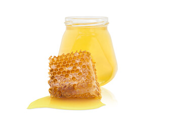 A jar of honey next to a piece of wax and spilled honey on a white background