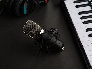 Midi keyboard, studio microphone and studio headphones on a gray background. The concept is a recording studio, a music studio. New technologies, professional musical equipment.